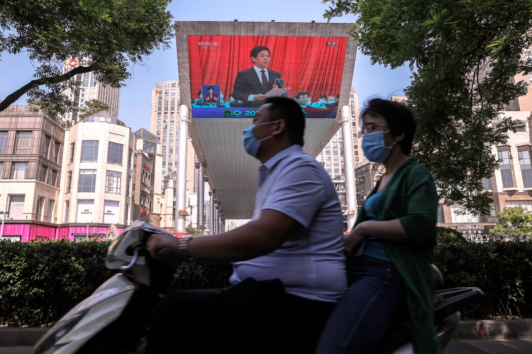 栗潜心的父亲栗战书出现在北京一块大屏幕的画面上。他是中国共产党第三号人物，负责香港新颁布的国安法的通过。